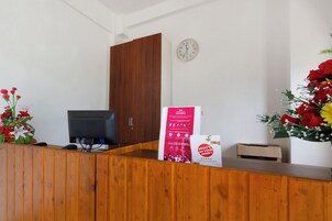 Una recepción con un ordenador, un reloj y un cartel.