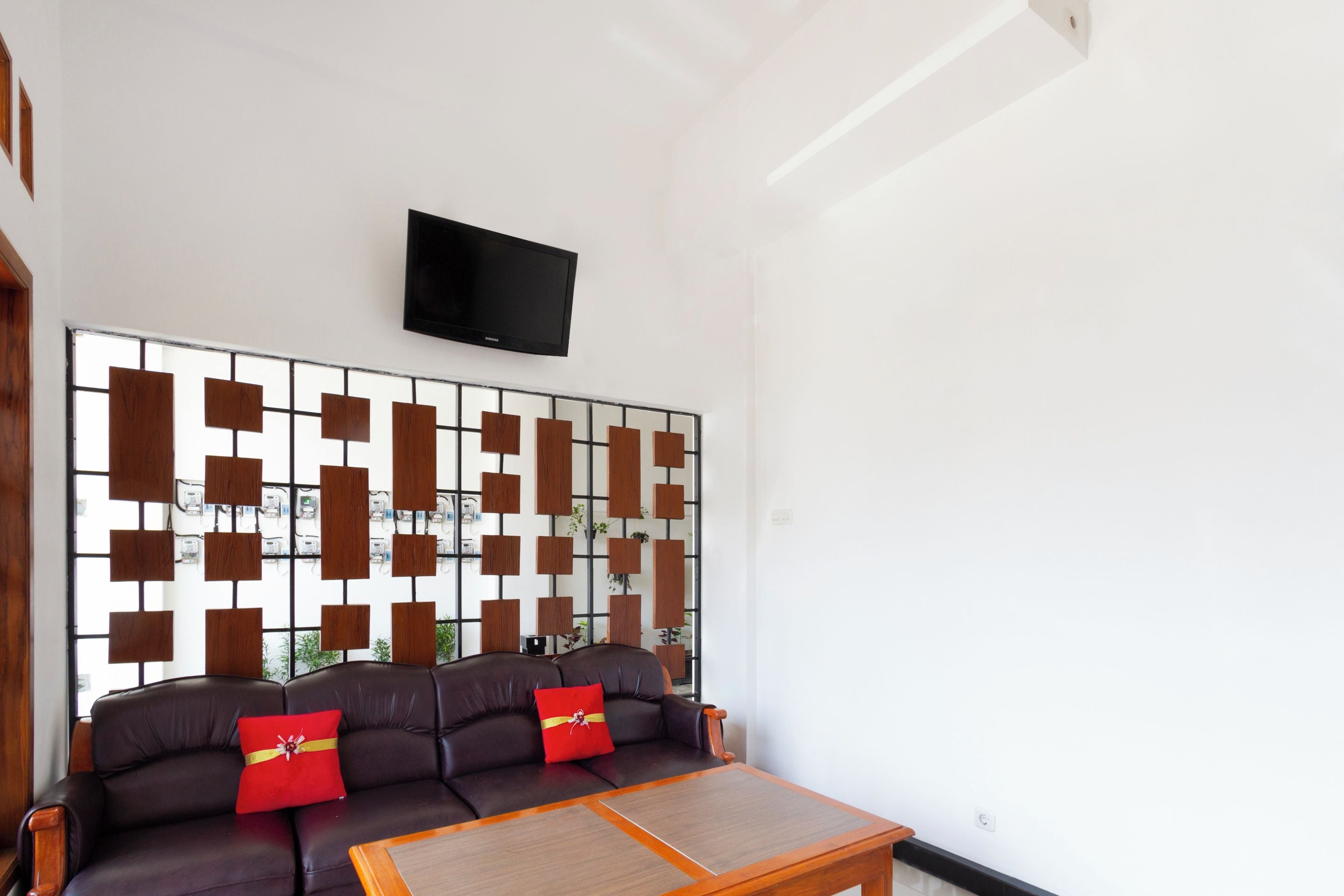 Un salon moderne avec un canapé en cuir marron, une table basse en bois et un panneau décoratif mural.
