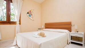 Una habitación de hotel con cama, mesita de noche, lámpara y un adorno en la pared.