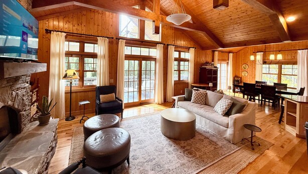 A spacious living room with wooden beams, a fireplace, a sofa, and a dining area. - Cashiers, NC Home on Golf Course w Trillium Club Access, Fast WiFi, Kid-Friendly (Cashiers)