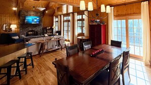 A wooden interior with a stone fireplace, wooden ceiling, and large windows. - Cashiers, NC Home on Golf Course w Trillium Club Access, Fast WiFi, Kid-Friendly (Cashiers)