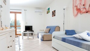 Un salon moderne et bien éclairé, avec un canapé, un téléviseur et une table à manger.