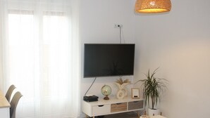 Un salon moderne avec un téléviseur à écran plat, une table basse blanche et une plante en pot.