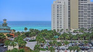 A hotel with a parking lot, palm trees, and a view of the ocean. - Lake View ~ Studio ~ Community Pool ~ Family Friendly (Miramar Beach)