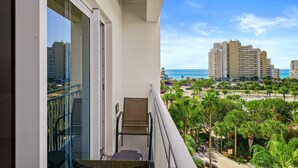 A balcony with a chair, a view of a coastal area with buildings and palm trees. - Lake View ~ Studio ~ Community Pool ~ Family Friendly (Miramar Beach)