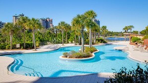 A swimming pool with a curved design, surrounded by palm trees and lounge chairs. - Lake View ~ Studio ~ Community Pool ~ Family Friendly (Miramar Beach)
