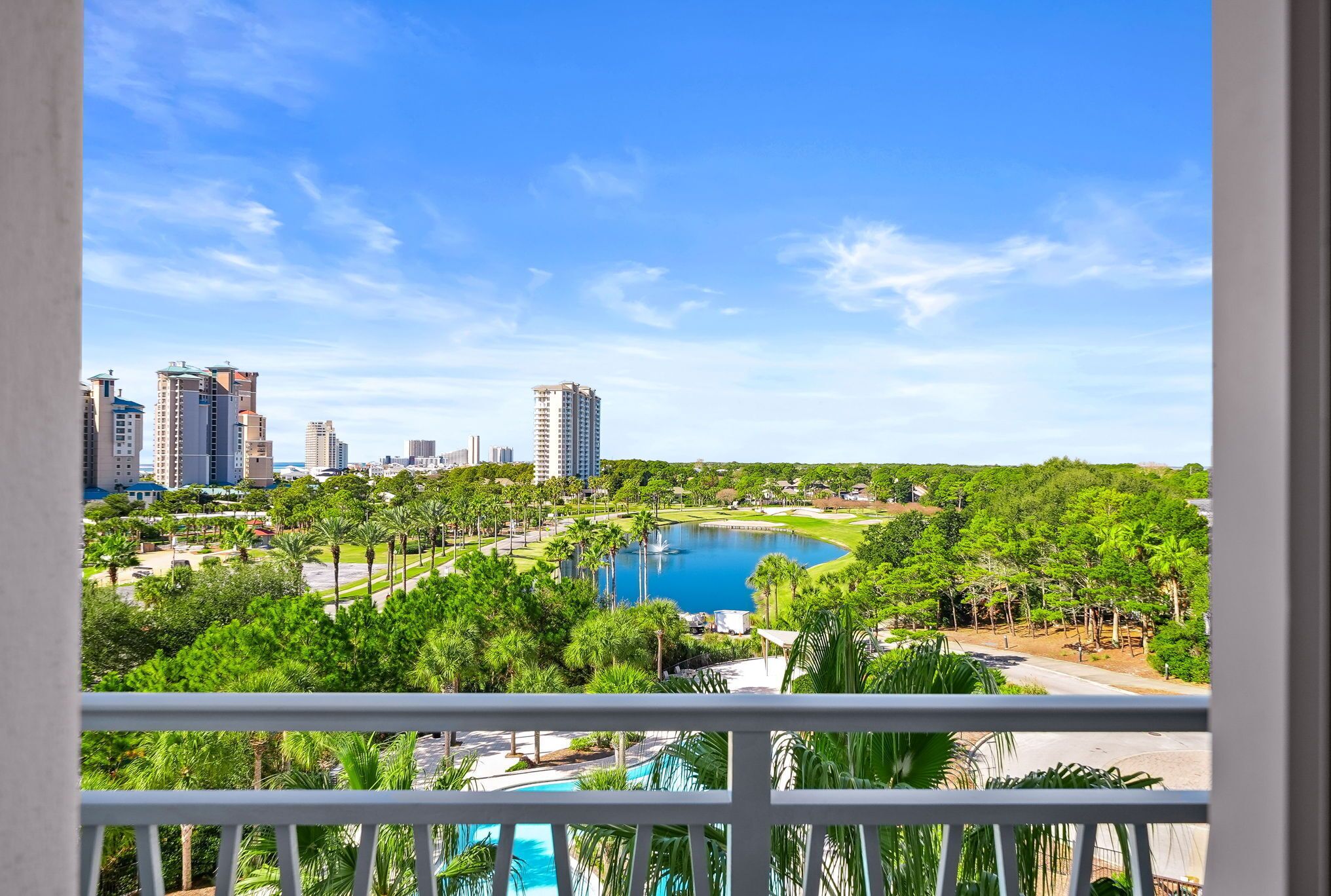 A view from a balcony overlooking a cityscape with tall buildings, a lake, and a golf course.