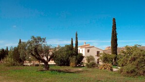 Un paysage rural avec un seul bâtiment entouré d’arbres et de champs ouverts.