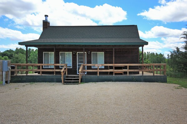 Een houten chalet met een grindpad en een houten terras.