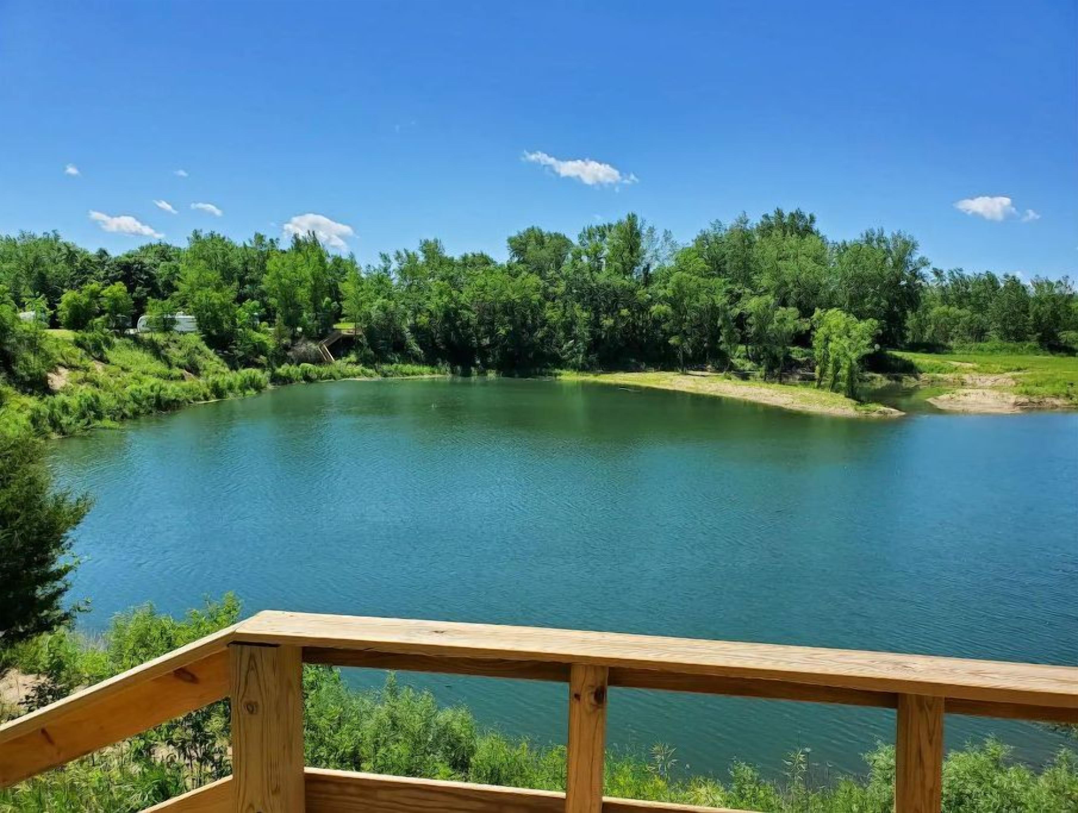 Un lago tranquilo rodeado de exuberante vegetación, visto desde una terraza de madera.
