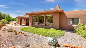 A modern house with a patio, large windows, and a garden with cacti. - Experience luxury at Sedona Star View, a 3-bed home with stunning red rock views. (Sedona)