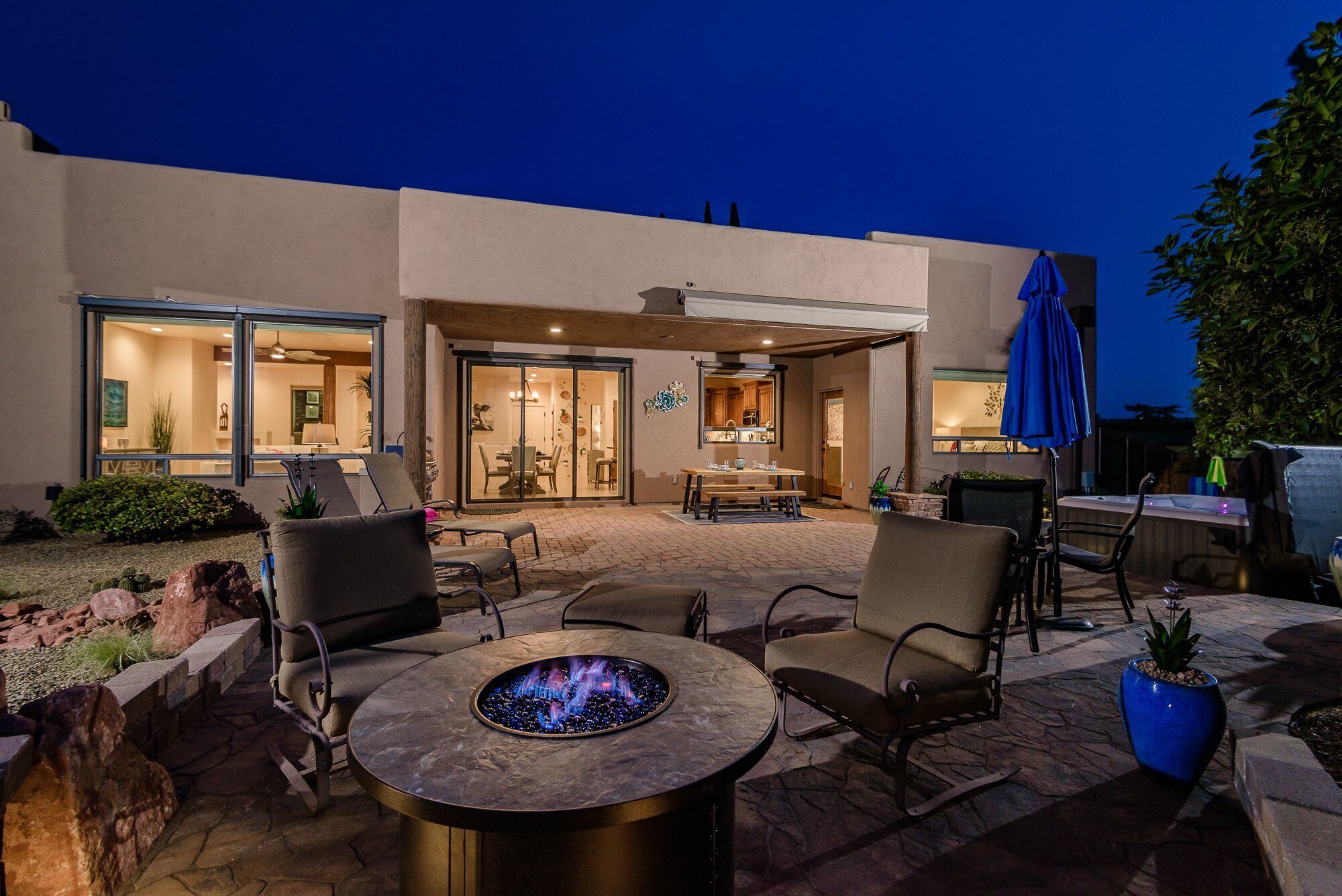 Un espace patio aménagé avec des sièges d’extérieur, un foyer et une vue sur l’intérieur de la maison.