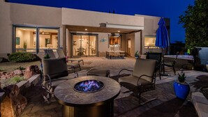 Un patio con mobiliario exterior, una fogata y vistas al interior de la casa.