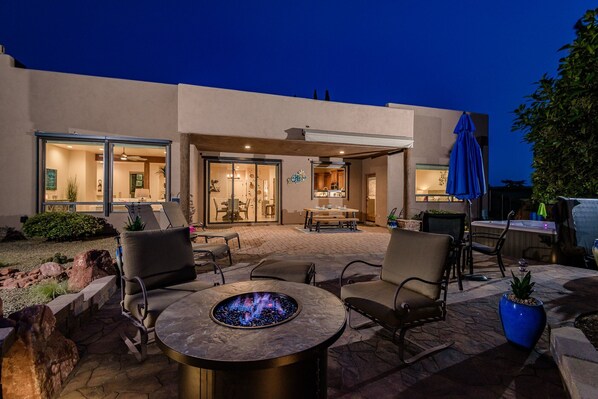 A patio area with outdoor seating, a fire pit, and a view of the house's interior.