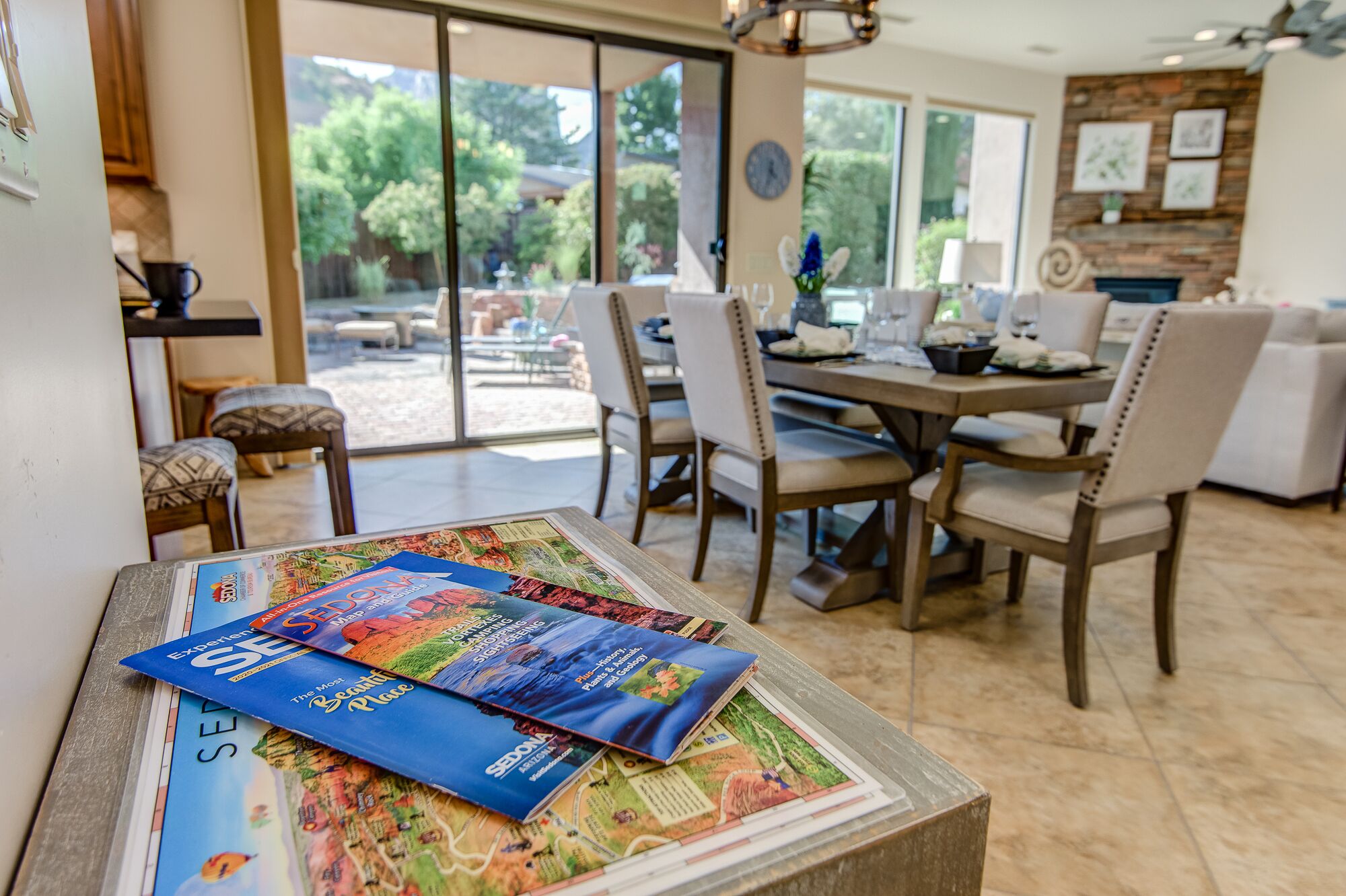 Un coin repas avec une table dressée pour quatre personnes, des chaises et une vue sur l’extérieur grâce à de grandes fenêtres.