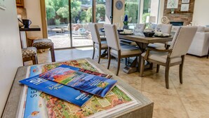 Comedor con una mesa dispuesta para cuatro sillas y vistas al exterior a través de amplios ventanales.