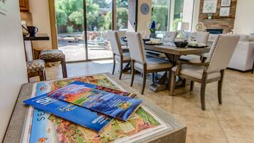Un coin repas avec une table dressée pour quatre personnes, des chaises et une vue sur l’extérieur grâce à de grandes fenêtres.