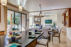 A modern kitchen with a dining area, featuring a large island, pendant lighting, and a stone accent wall.
