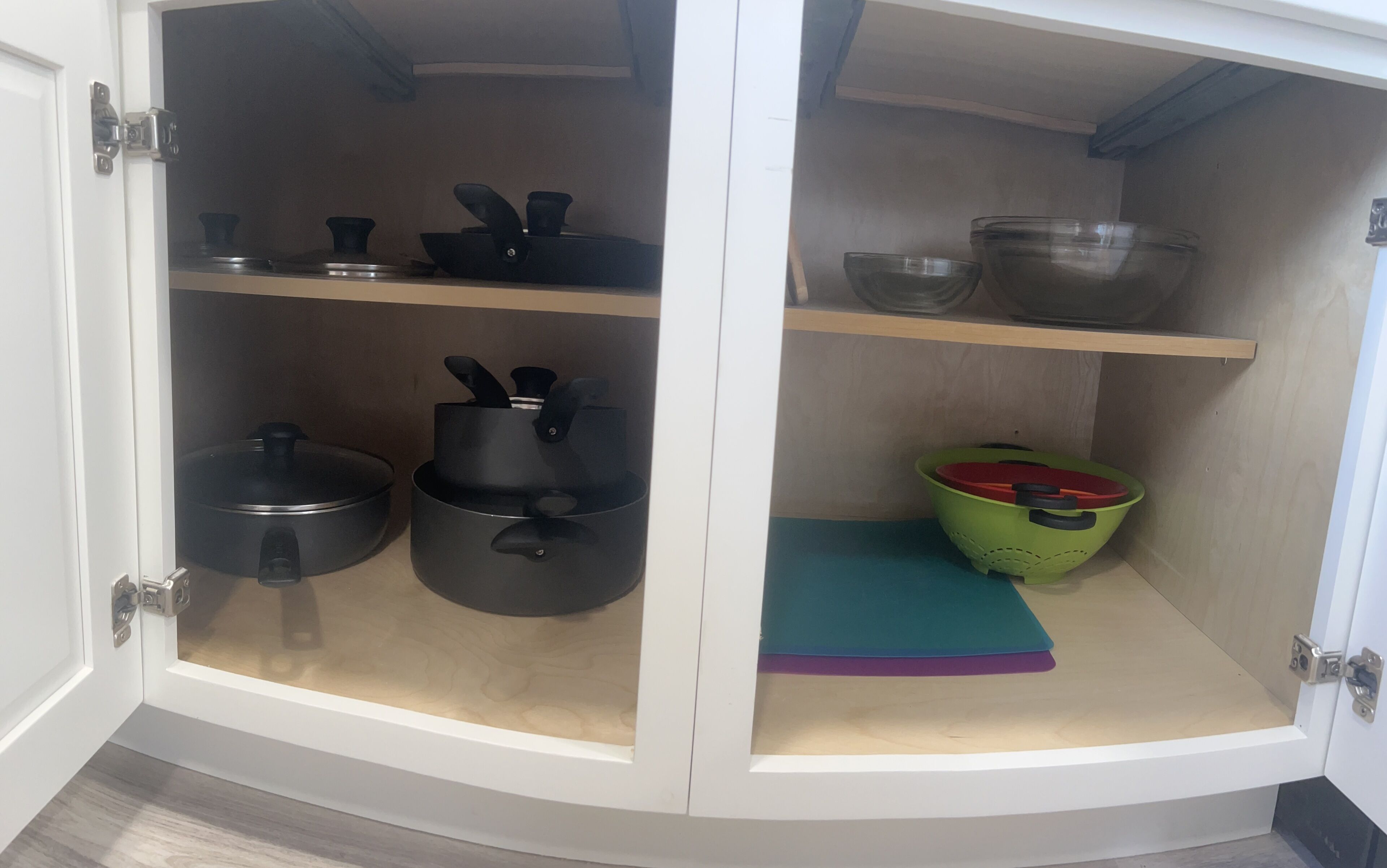 Ein Küchenschrank mit drei Einlegeböden, auf denen Geschirr und Küchenutensilien stehen.