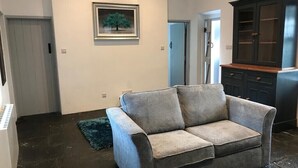 Un salón con un sofá gris, un cuadro en la pared y un mueble de madera oscura.