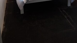 Una cama individual con ropa de cama blanca y dos toallas enrolladas.