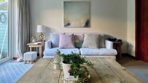 A living room with a sofa, coffee table, and a painting on the wall. - Apple Cottage - Central Frome - Family Friendly (Somerset)