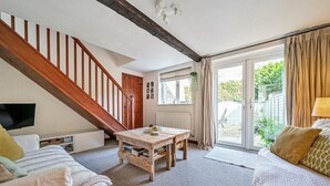 A cozy living room with a wooden staircase, a television, a coffee table, and a sofa. - Apple Cottage - Central Frome - Family Friendly (Somerset)