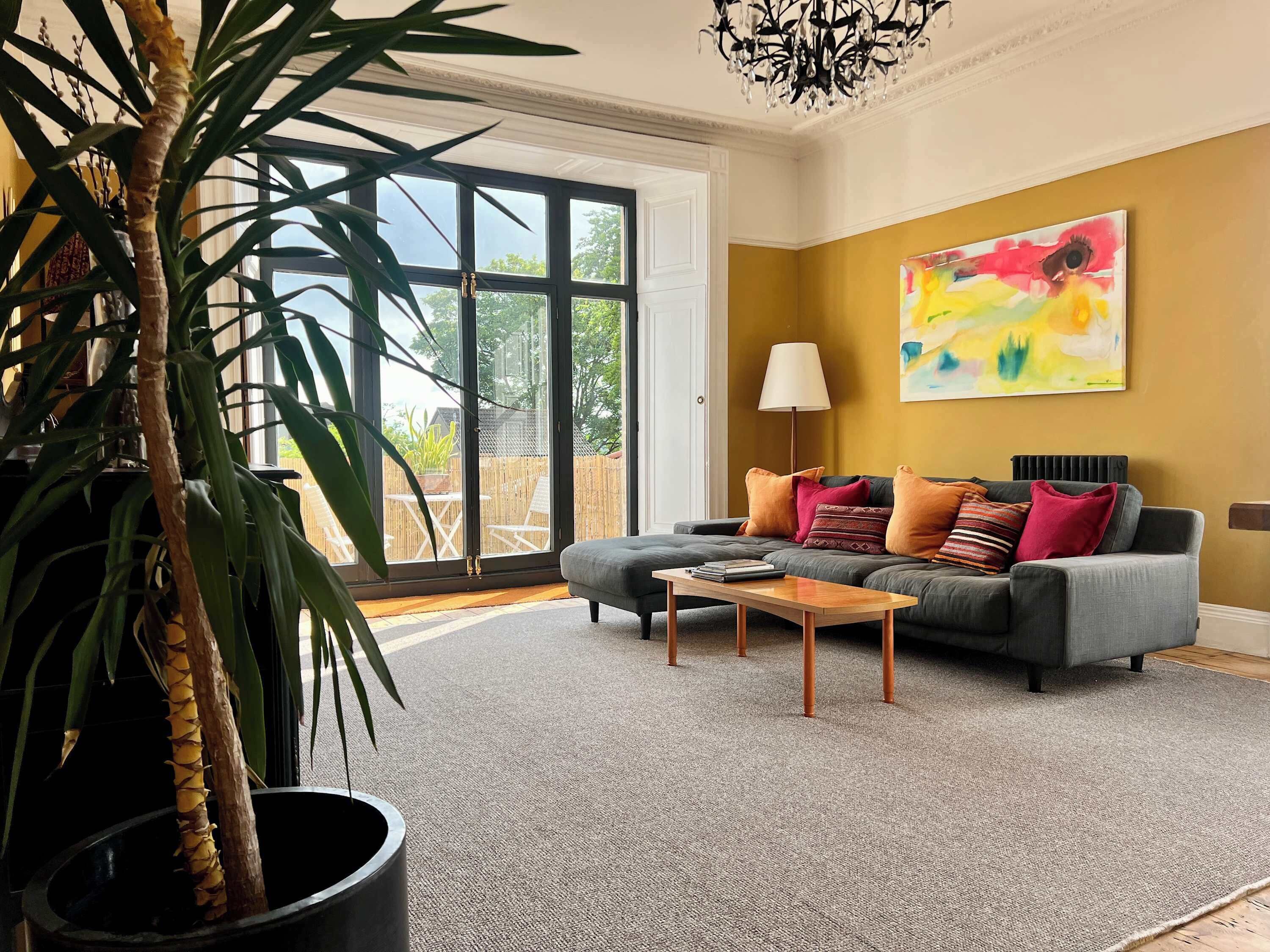 A living room with a grey sofa, a coffee table, and a large window.