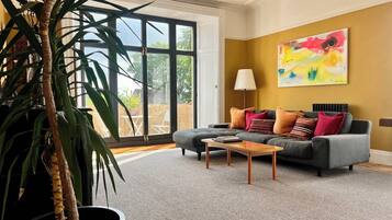 A living room with a grey sofa, a coffee table, and a large window.