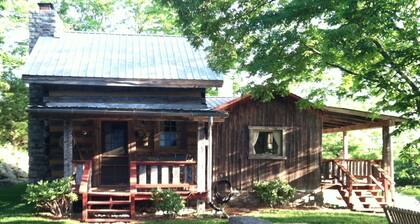 1800’s restored log cabin on 26 private rolling wooded acres with sunset views