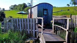 A rustic wooden structure with a small porch and a wooden bridge leading to it. - Beavers Lodge on top of the Shropshire Hills (Craven Arms)