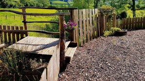 A wooden fence with a bench and flower pots, surrounded by a gravel path and greenery. - Beavers Lodge on top of the Shropshire Hills (Craven Arms)