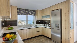 Una cocina moderna con armarios de madera, un refrigerador de acero inoxidable, una cafetera y vistas al mar.