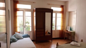 Ein Schlafzimmer mit zwei Betten, einem Holzschrank, einem Schreibtisch und einem Stuhl.