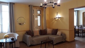 Ein Wohnzimmer mit einer Couch, einem kleinen Tisch mit Blumen in einer Vase, einem Spiegel und einer Kandelaber.