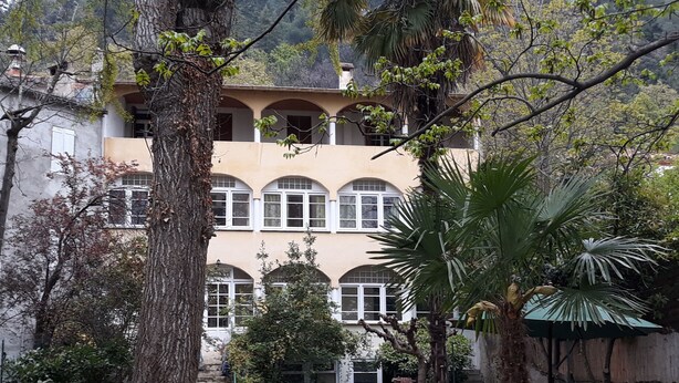 Ein mehrstöckiges Gebäude mit einer beige farbenen Fassade, Bogenfenstern und Balkonen.