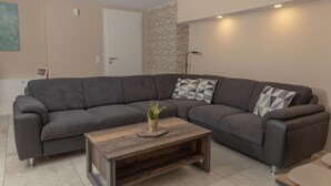 A modern living room with a gray sectional sofa, a wooden coffee table, and a small potted plant.