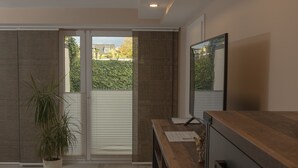 A modern kitchen with a wooden countertop, a potted plant, and a sliding glass door leading to a balcony.