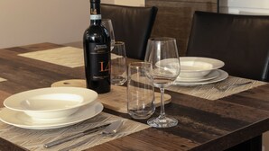 A dining table set with white plates, cutlery, and a bottle of wine.