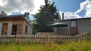A rustic cabin with a wooden exterior, a chimney, and a wooden fence. - Cabin Retreat With Beavers on Shropshire Hills (Craven Arms)