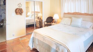 Een slaapkamer met een groot bed, een spiegel, een stoel en een nachtkastje met een lamp.