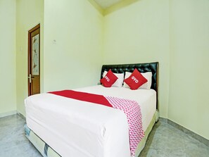 A neatly made bed with a white and red bedspread, two red pillows with 'OYO' text, and a dark headboard. - OYO 3214 Puri Amalia (Banyuwangi)