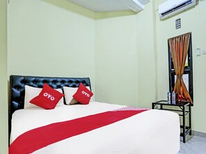 A hotel room with a bed, a black headboard, and a red and white bedspread. - OYO 3214 Puri Amalia (Banyuwangi)