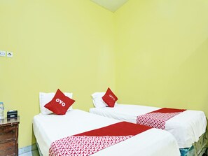 Hotellihuone, jossa on kaksi sänkyä. Kummassakin sängyssä on valkoiset lakanat ja punaiset tyynyt sekä punavalkoinen kuviollinen sängynpeite.