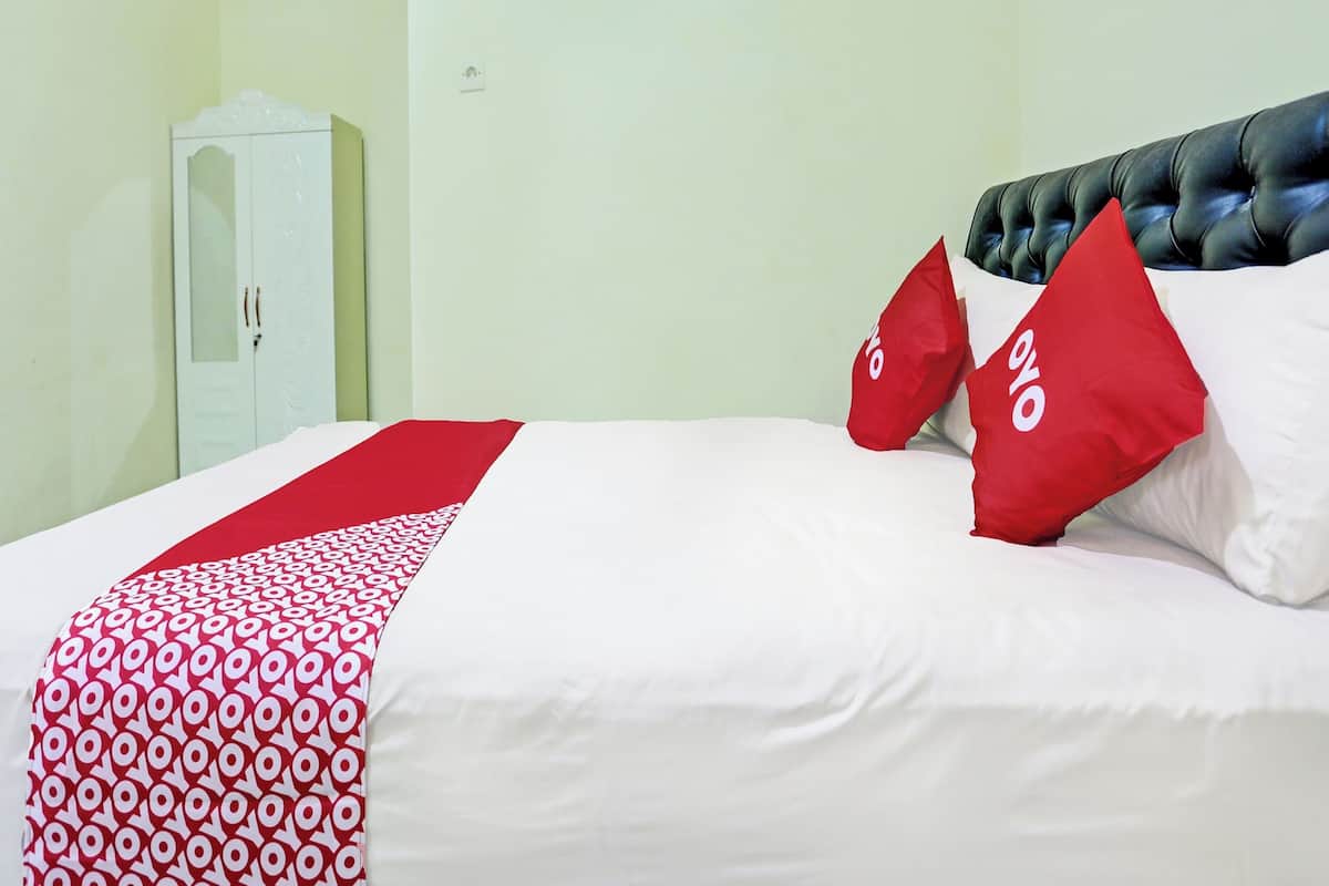 A hotel room with a bed, a wardrobe, and a red and white patterned bedspread.