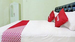 A hotel room with a bed, a wardrobe, and a red and white patterned bedspread. - OYO 3214 Puri Amalia (Banyuwangi)
