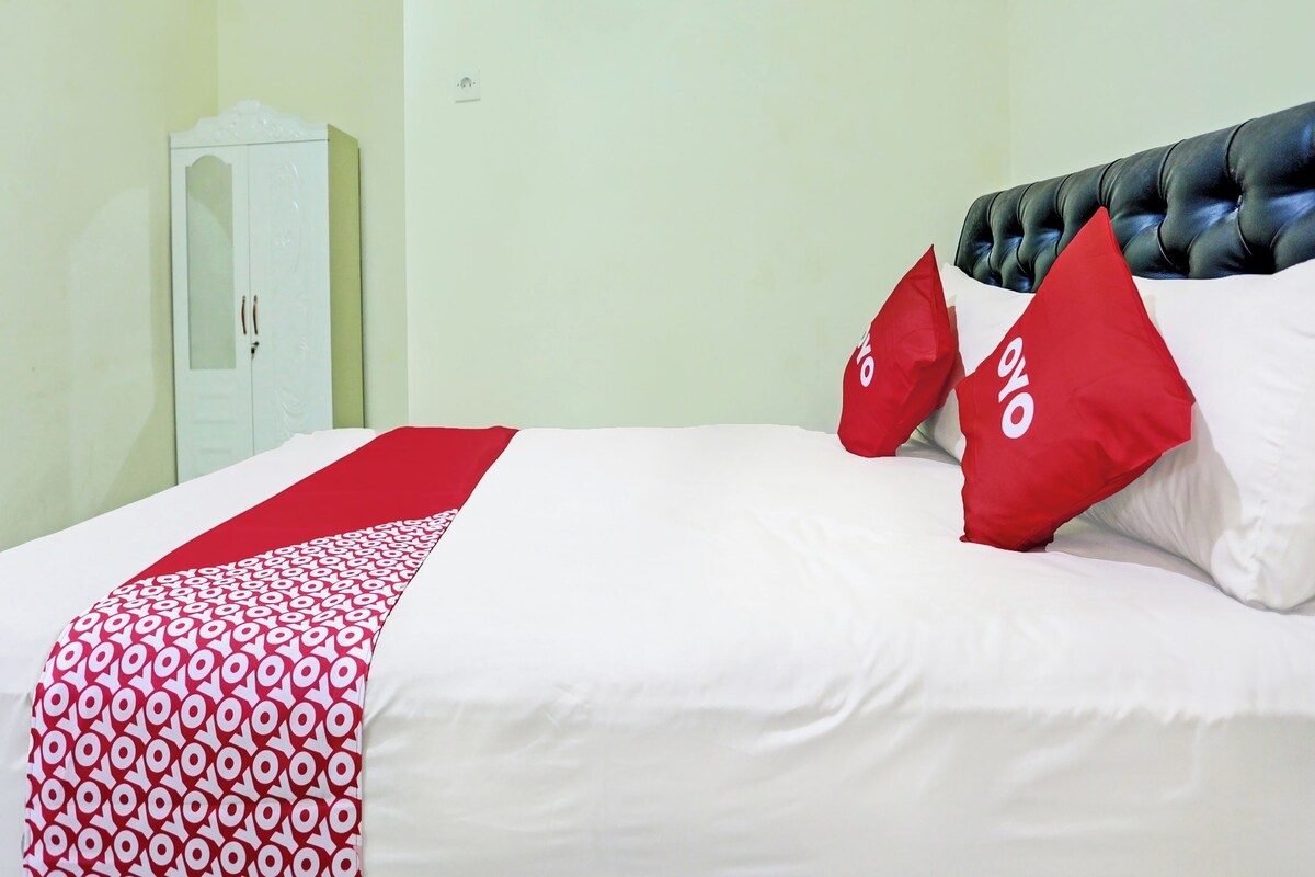 Une chambre d’hôtel avec un lit, une armoire et une couvre-lit à motifs rouges et blancs.