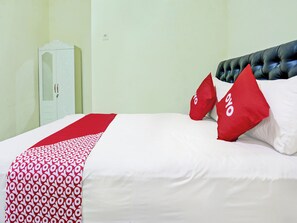 Une chambre d’hôtel avec un lit, une armoire et une couvre-lit à motifs rouges et blancs.