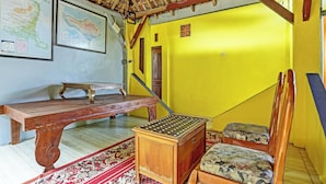 A room with a wooden desk, a map, a chair, and a patterned rug. - OYO 3214 Puri Amalia (Banyuwangi)