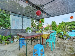 Un área de estar al aire libre con una mesa, sillas y plantas en macetas.